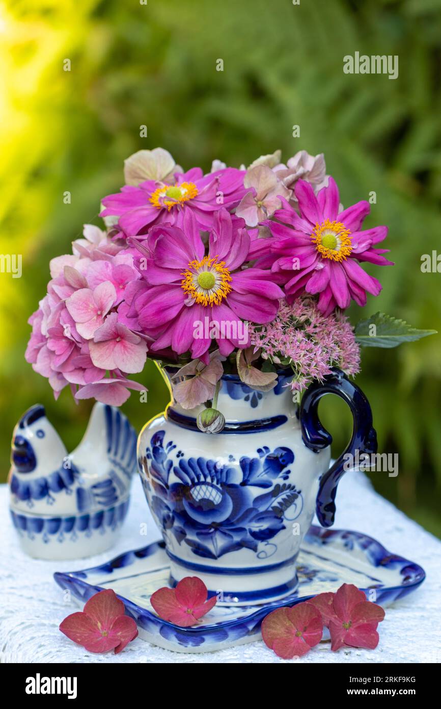 bouquet of pink japanese anemones and hydrangea flowers in rustic milk can Stock Photo