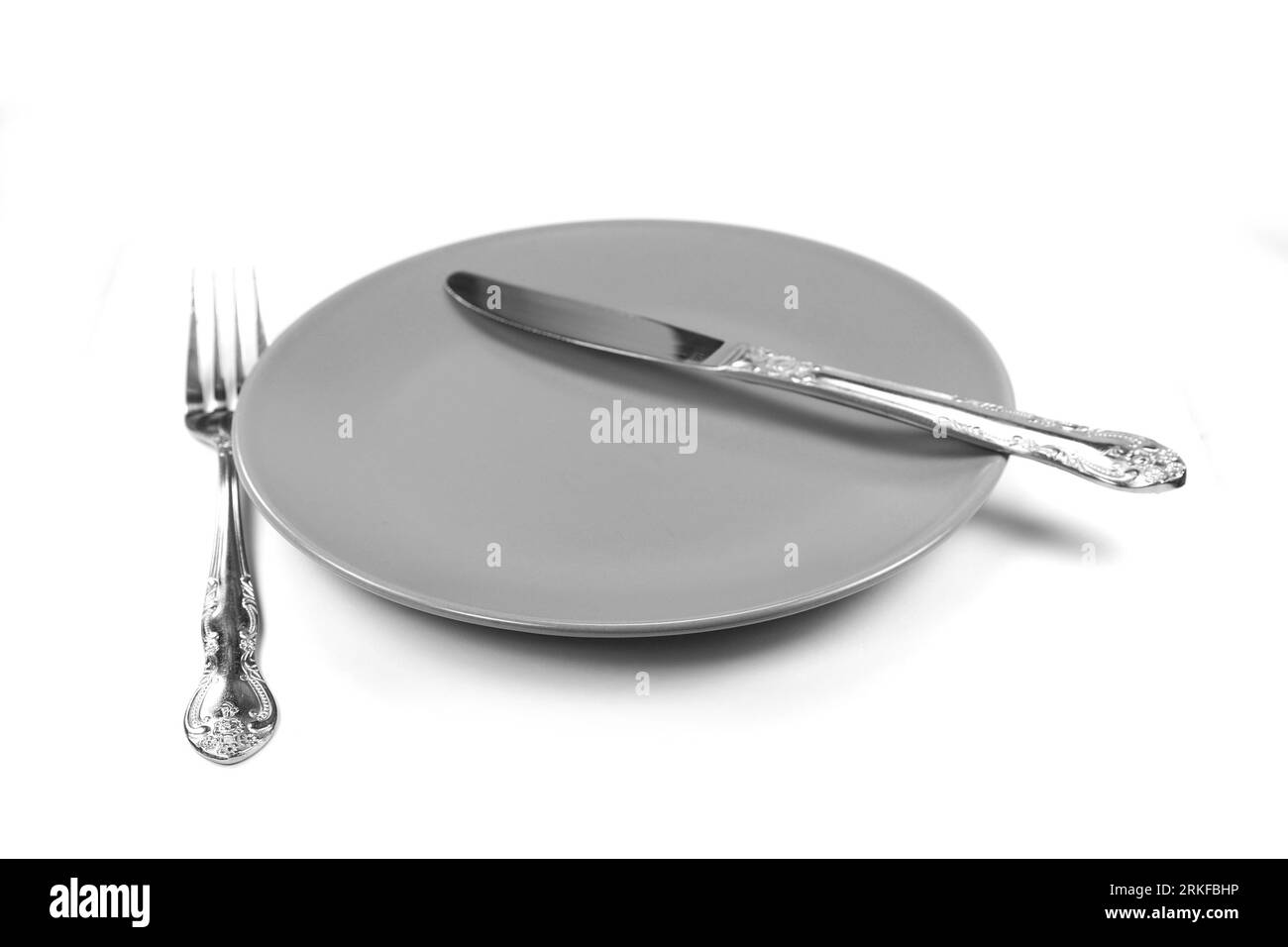 Empty plate with knife and fork isolated on white Stock Photo - Alamy