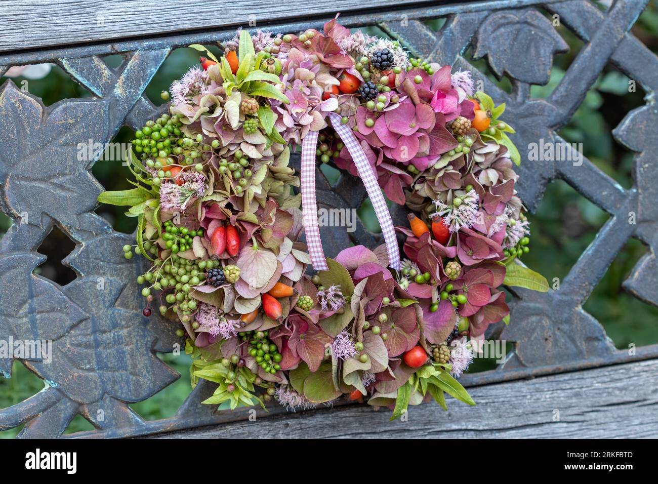 wreath of pink hydrangea flowers, rose hips, elderberries and hazel bush fruits Stock Photo