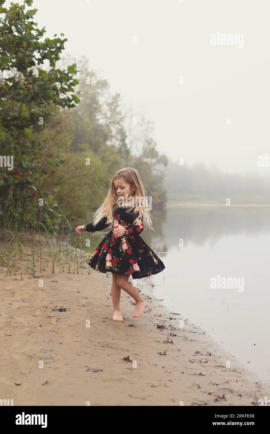 Graceful little girl dances by the lake in the morning fog Stock Photo