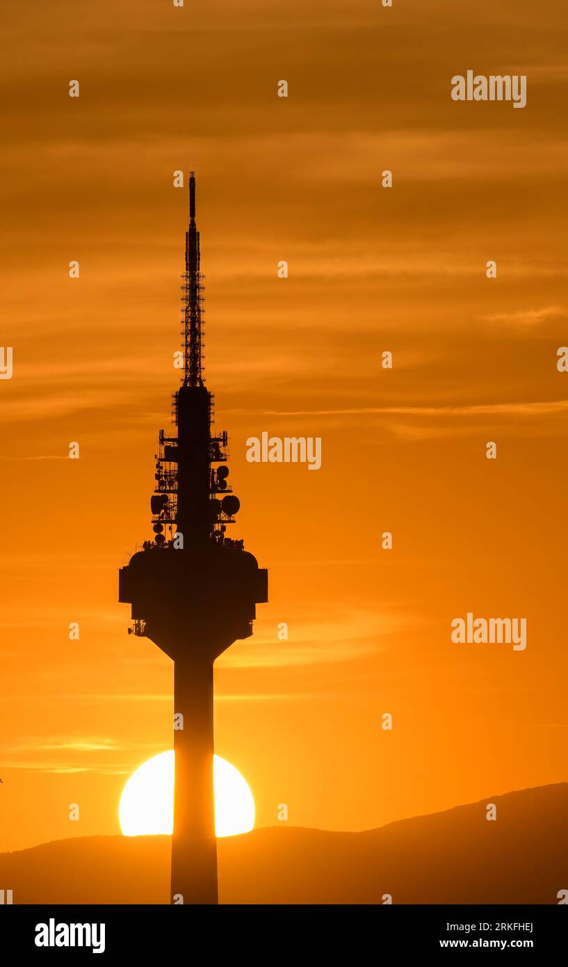 Sunset with the sun setting behind the base of a communications tower. Stock Photo