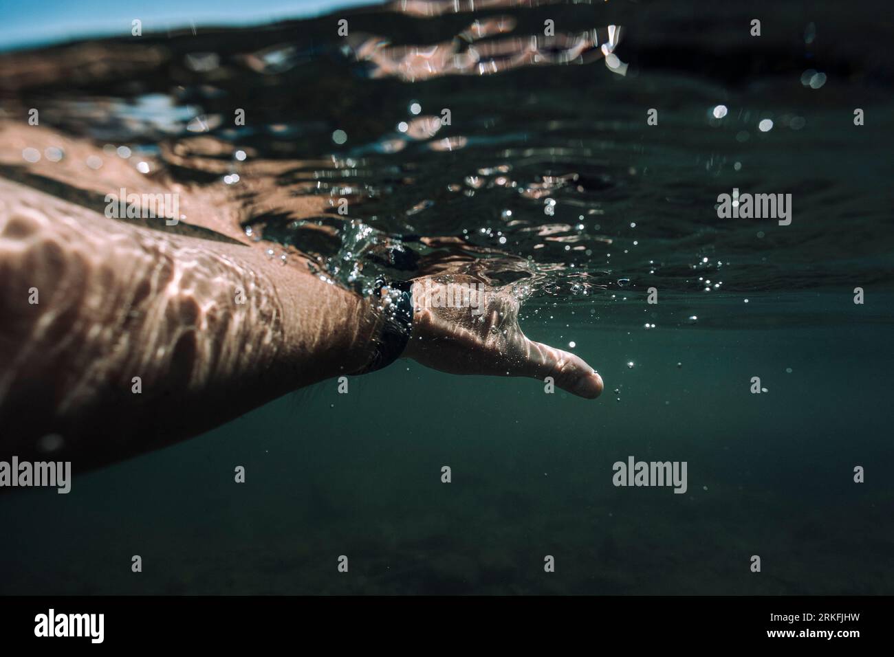 A hand goes through clear lake water. Stock Photo