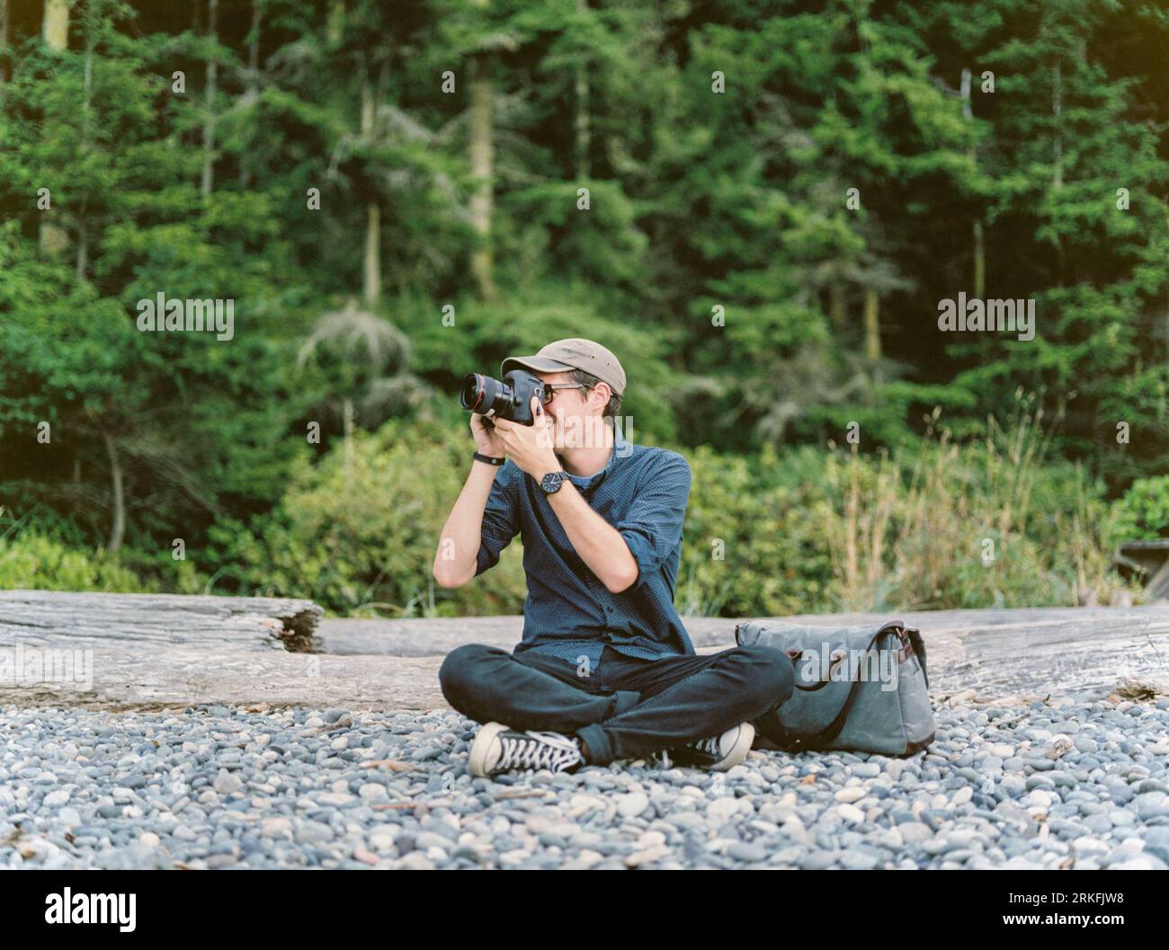 Man sitting on rocky coast in Oregon taking pictures. Stock Photo