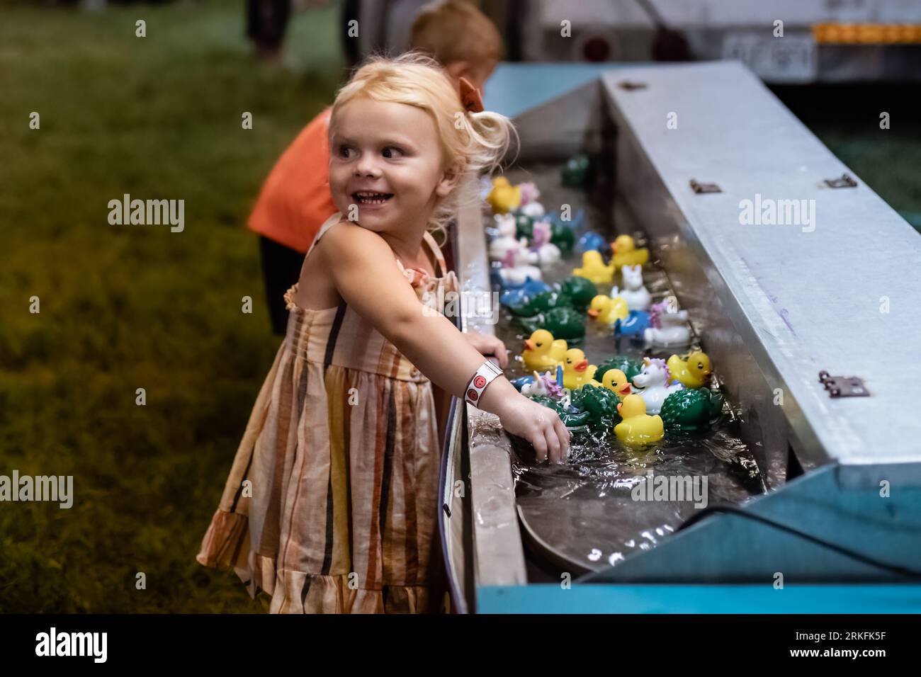 Children playing rubber duck game at carnival in the evening Stock