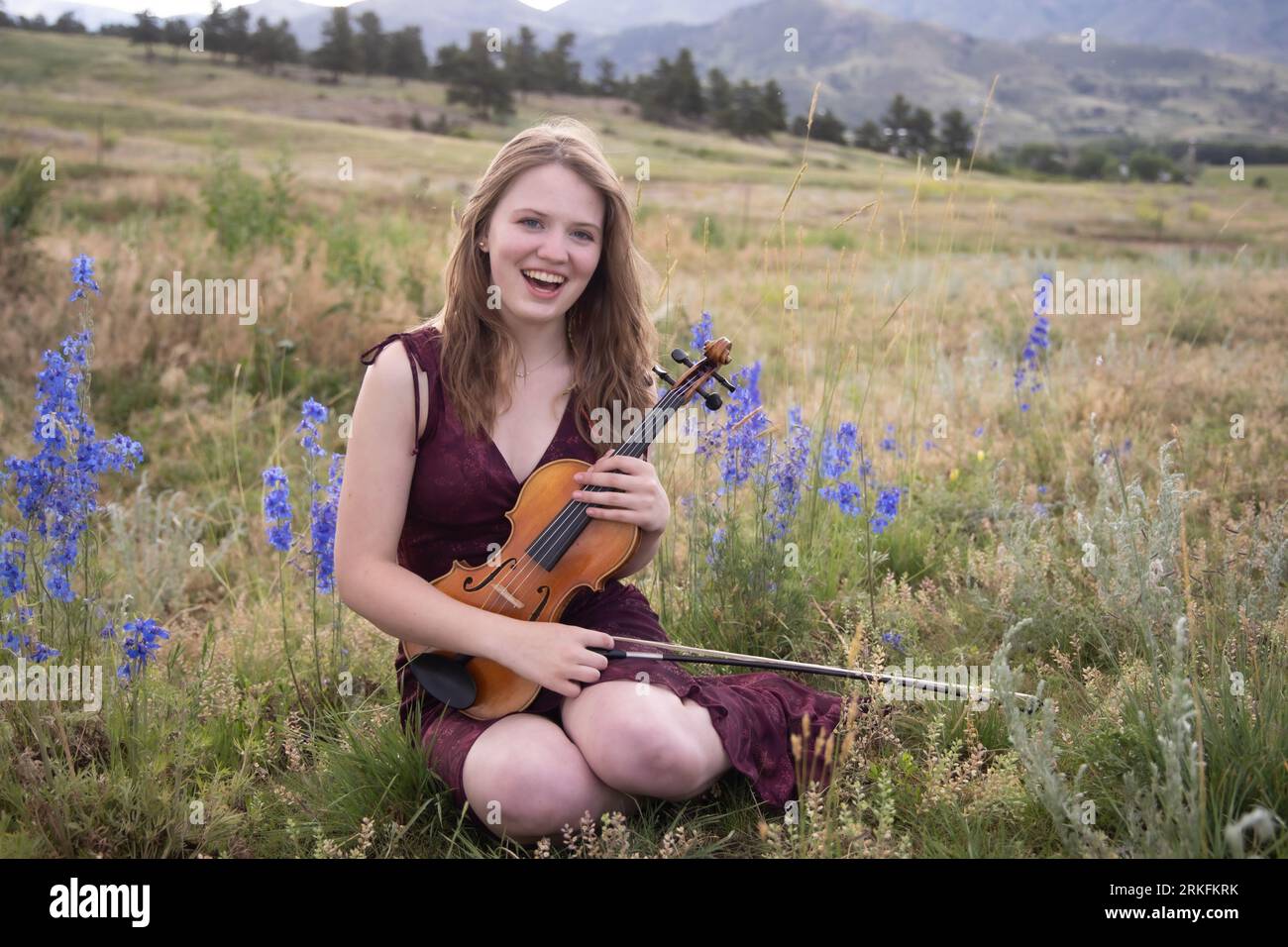 Teenage girl sitting in field with violin Stock Photo - Alamy