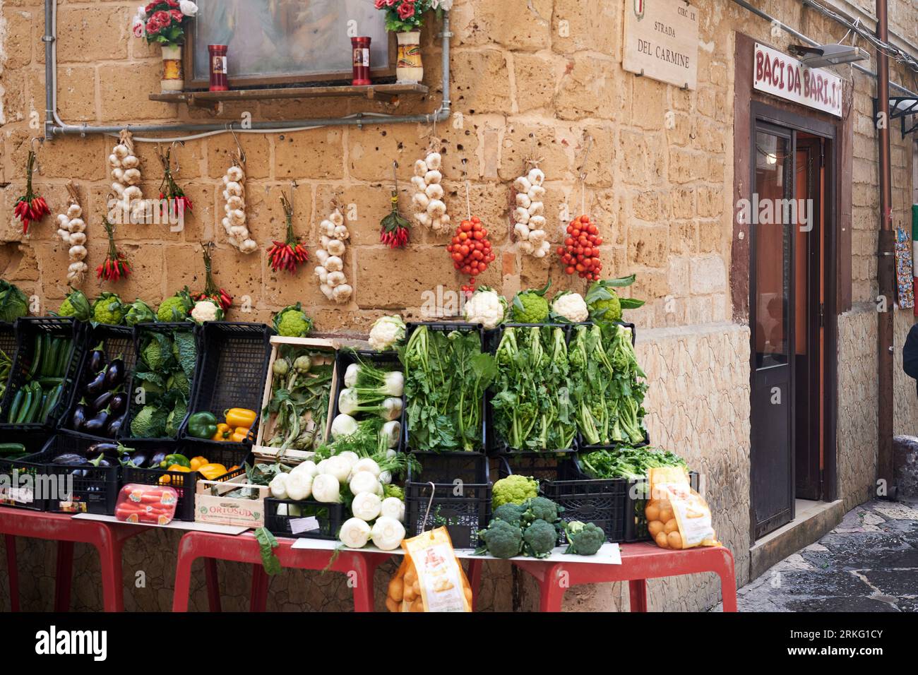 An array of vibrant, freshly picked fruits and vegetables arranged on a vendor's stall in an alleyway Stock Photo