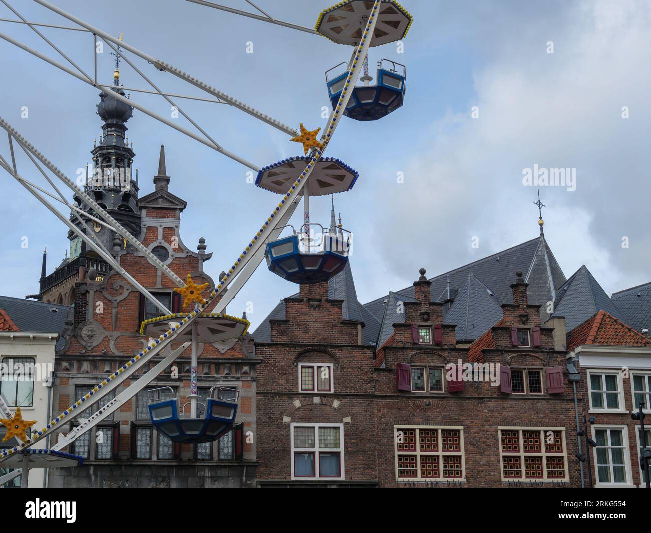 A colorful ferris wheel spinning in front of a historic skyline in