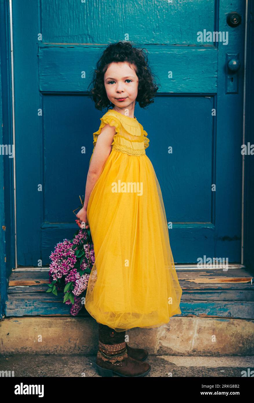 A vertical of a young girl in a bright yellow dress standing at a ...