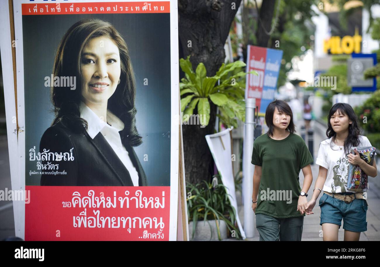 Bildnummer: 55565263 Datum: 02.07.2011 Copyright: imagoXinhua (110702) --  BANGKOK, July 2, 2011 (Xinhua) -- Two girls walks past a campaign poster in  Bangkok, Thailand, on July 2, 2011. Thailand will hold a