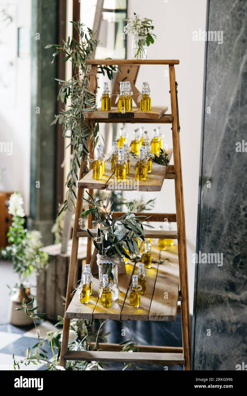 A wooden shelf displaying multiple varieties of oil containers with a bouquet of flowers beside it Stock Photo