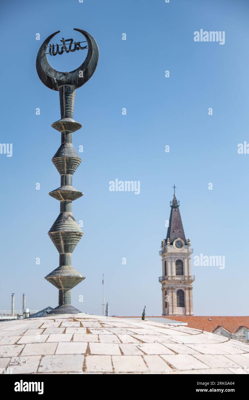 An impressive clock tower stands majestically atop a roof, its face gazing out over a grand domed building: Jerusalem Stock Photo