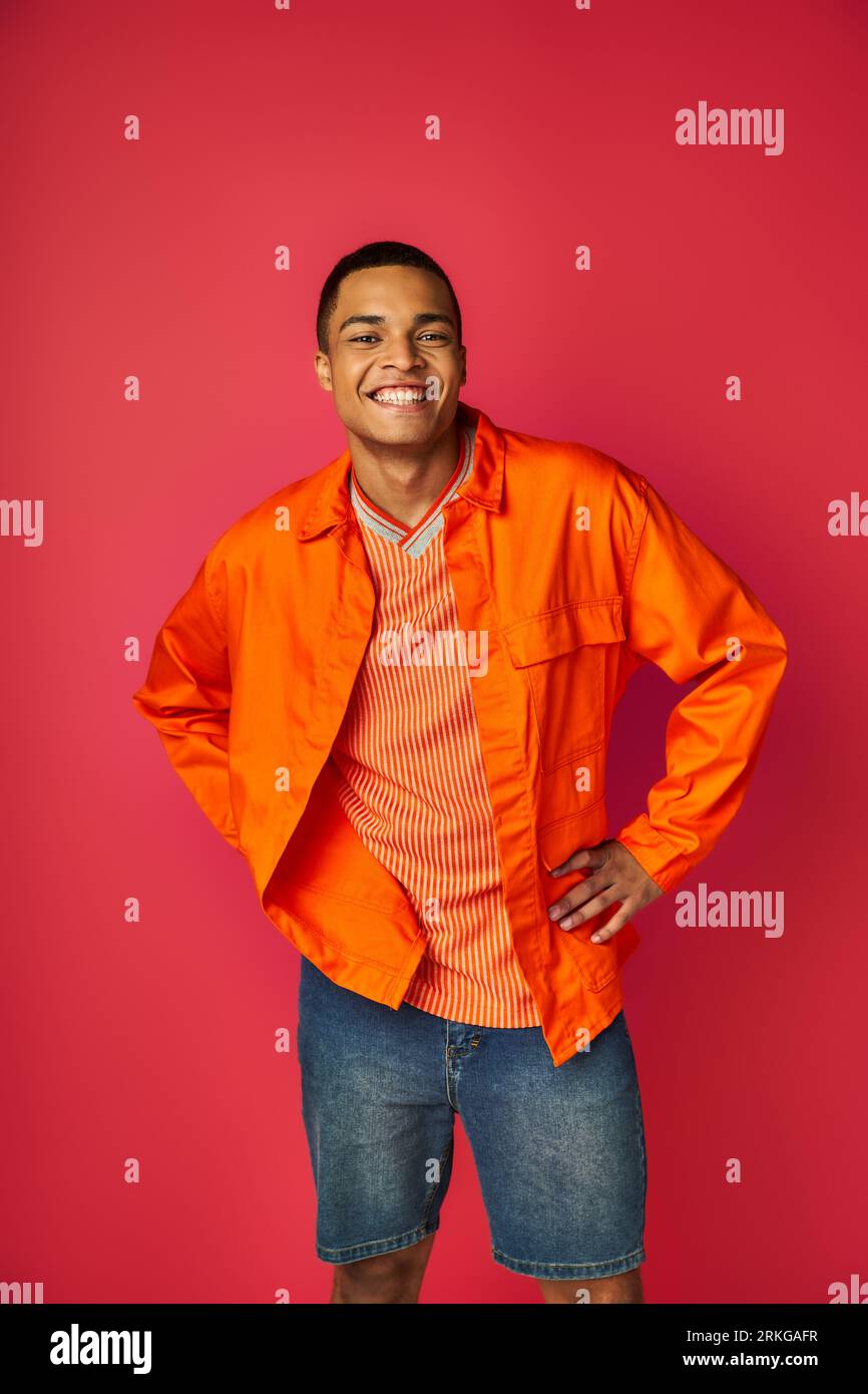 trendy african american guy in orange shirt standing with hands on hips ...