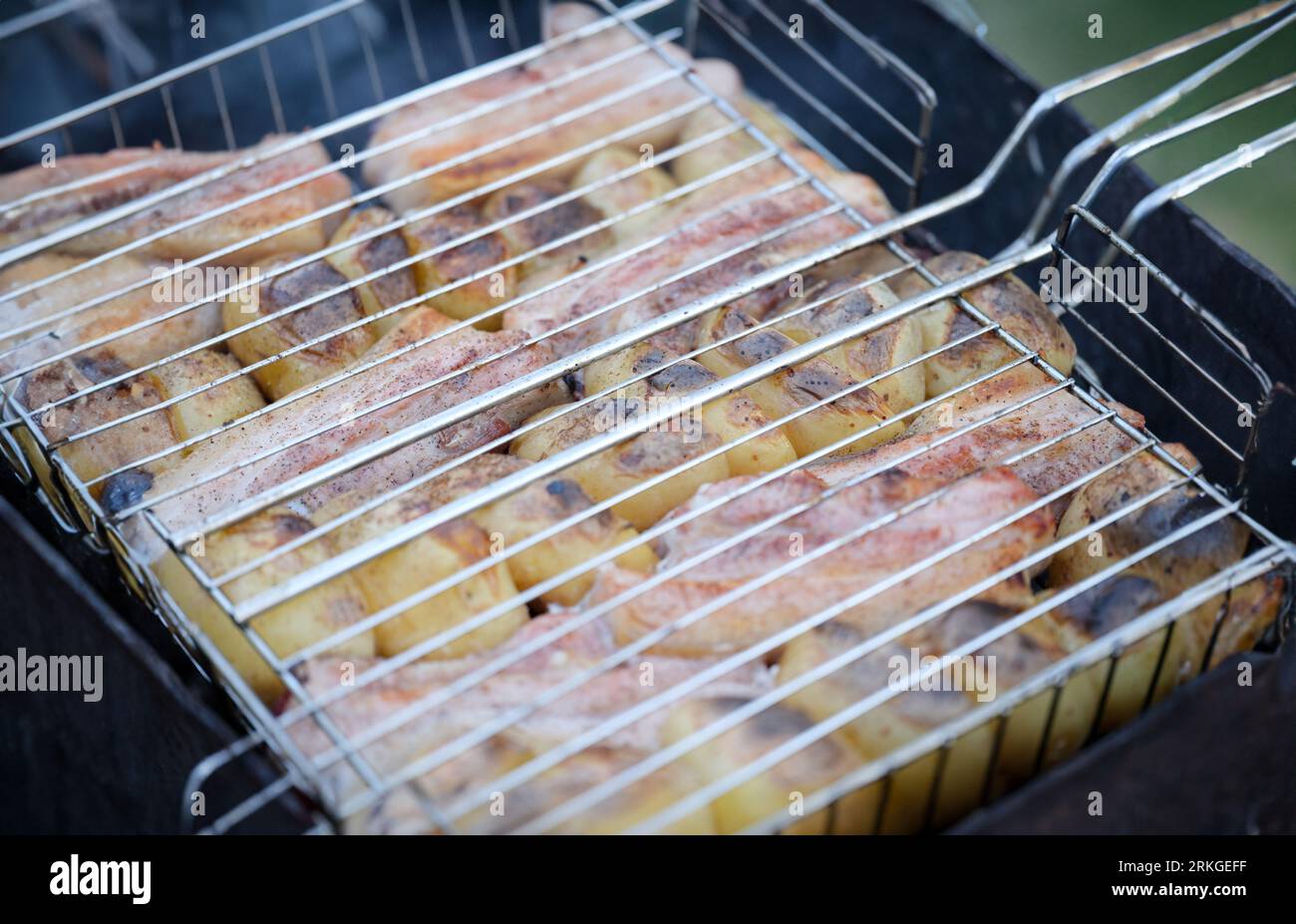 Roast pork and potatoes on wire rack over fire closeup Stock Photo - Alamy