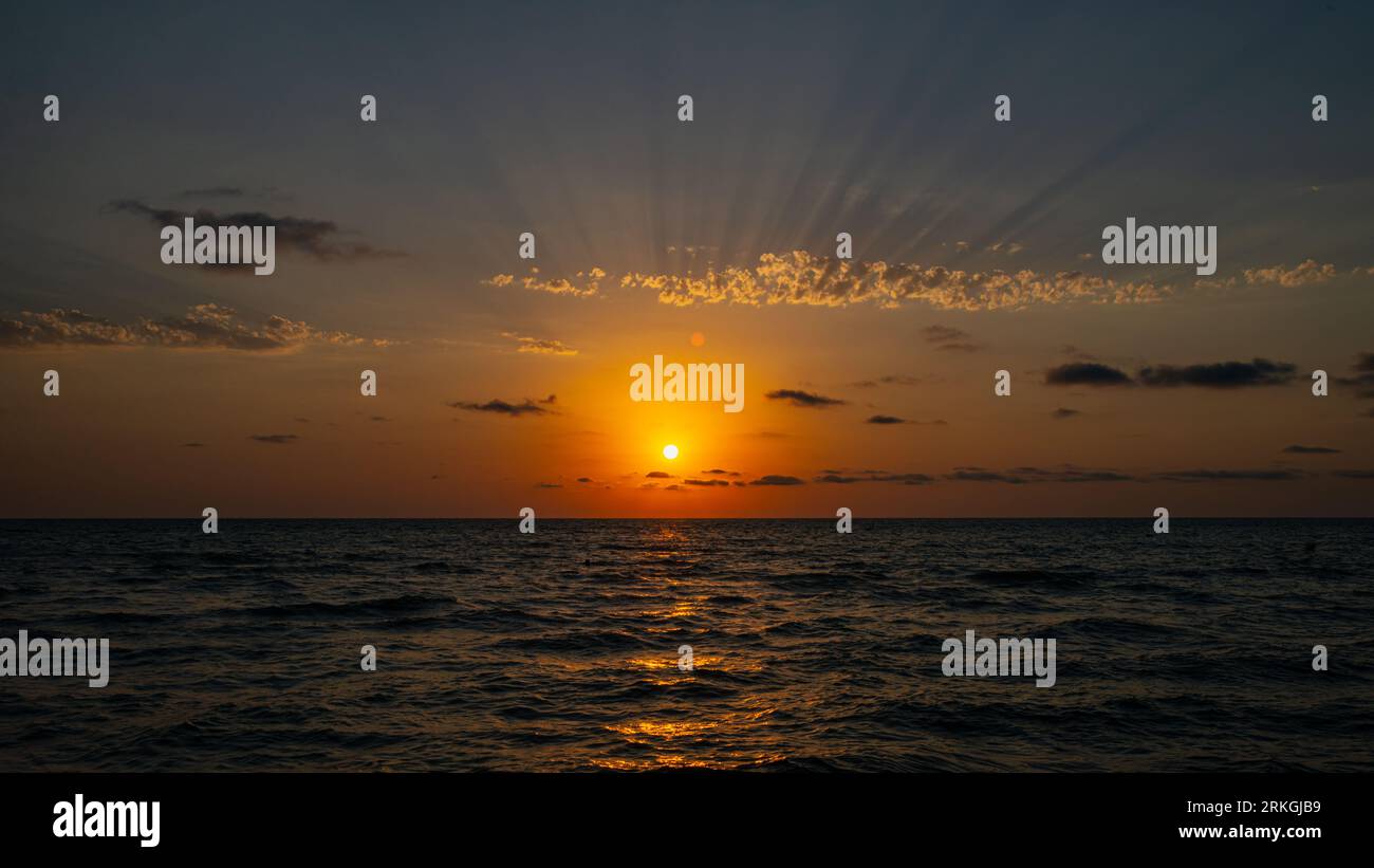 An idyllic beach scene featuring a golden sun setting over the Black ...