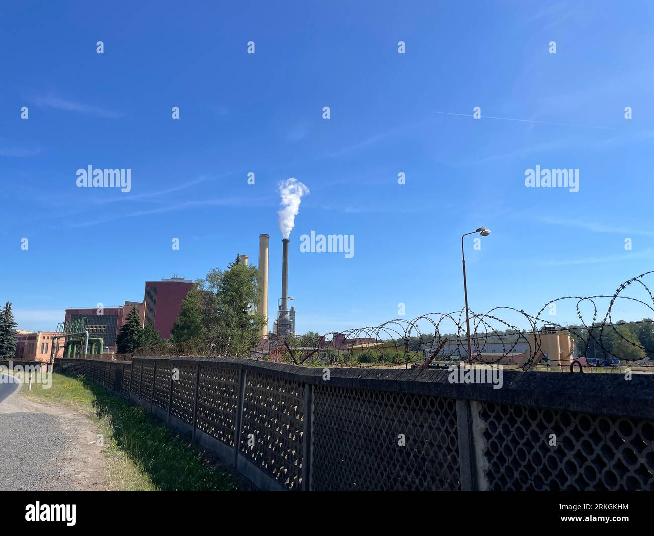 An industrial building with a smokestack emitting a large plume of smoke into the sky. It is a coal power plant in Tisova in the Czech Republic. Stock Photo