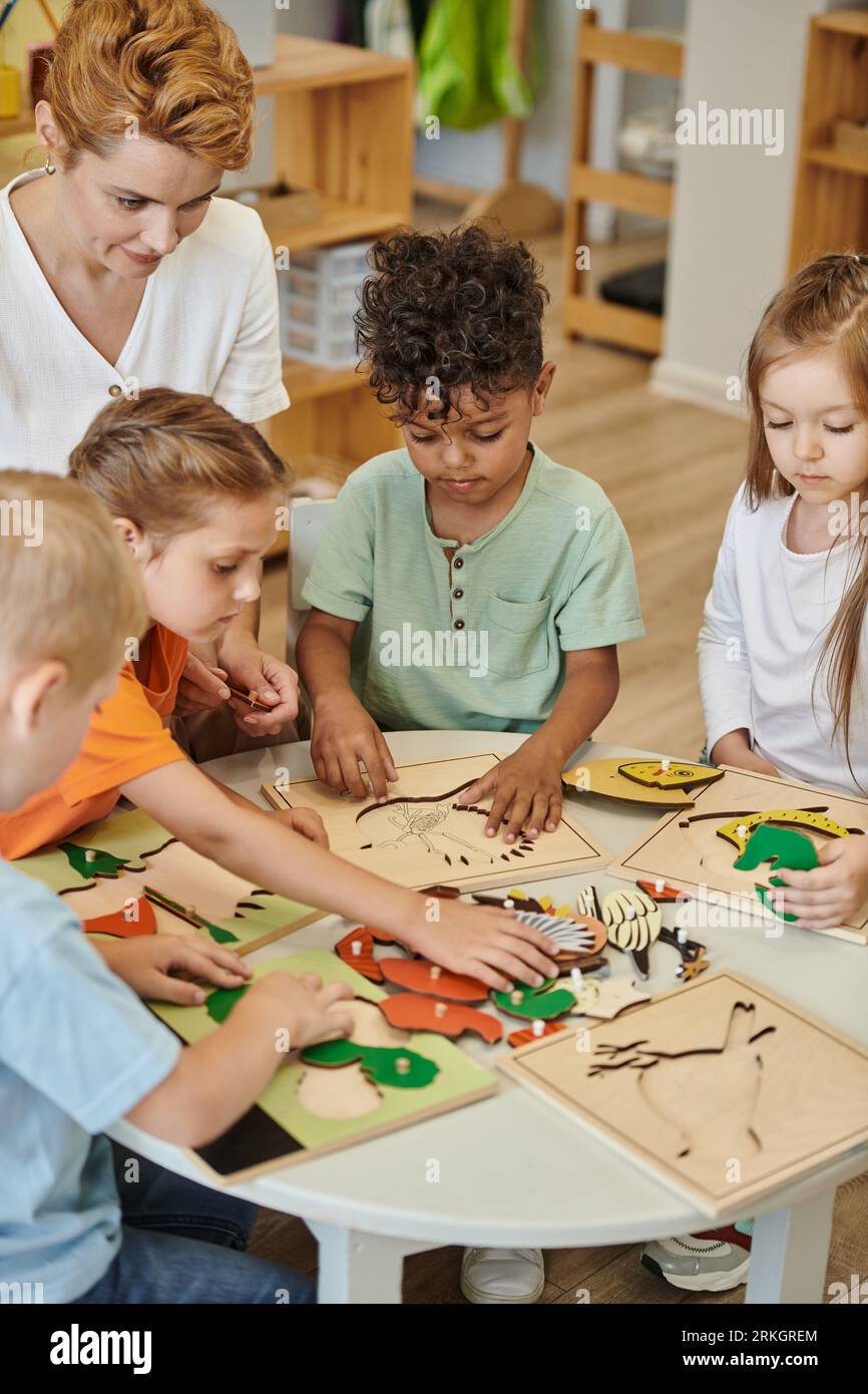 multiethnic kids and teacher playing with didactic materials in