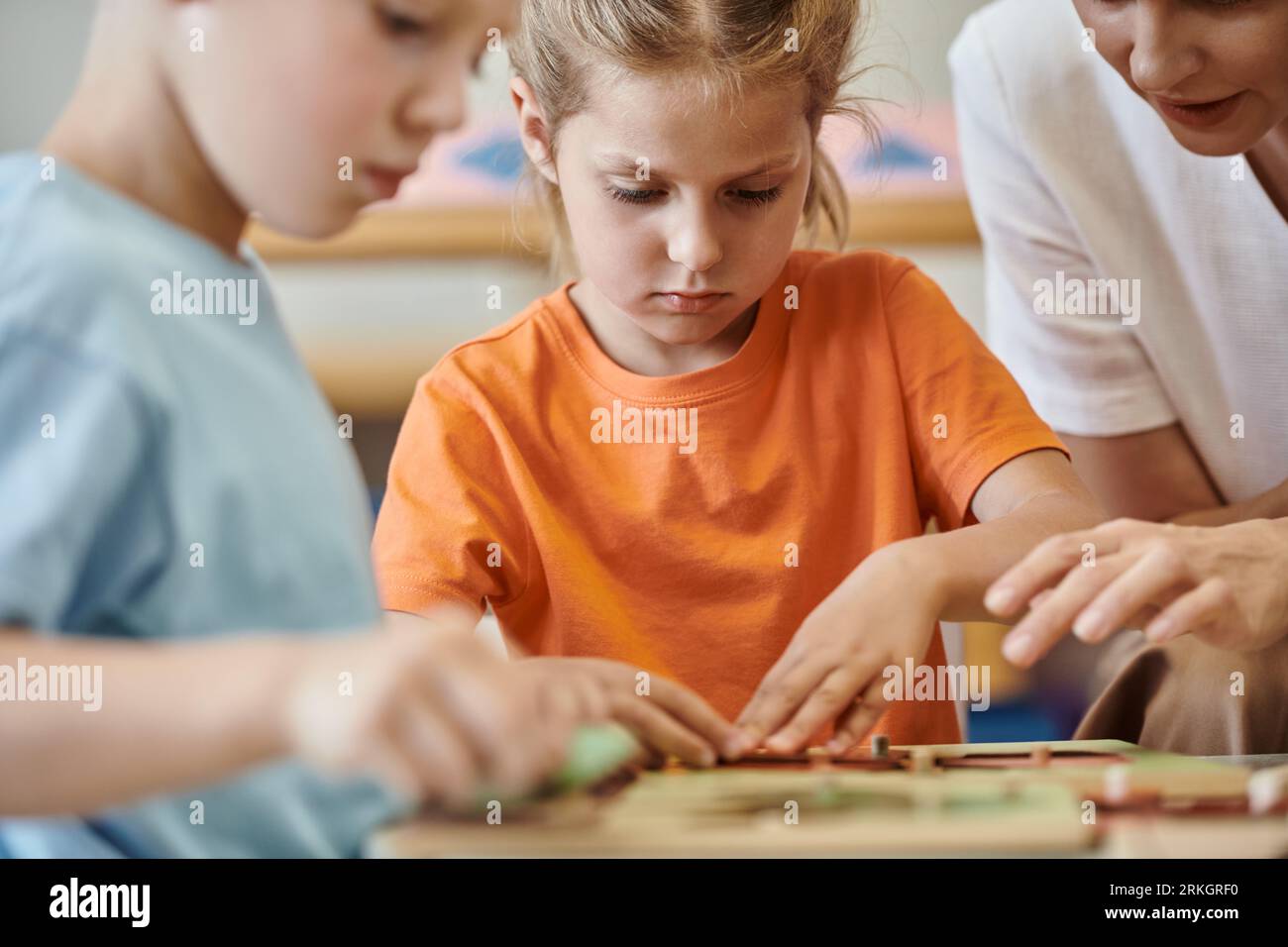 teacher talking to kids near blurred didactic materials on lesson in