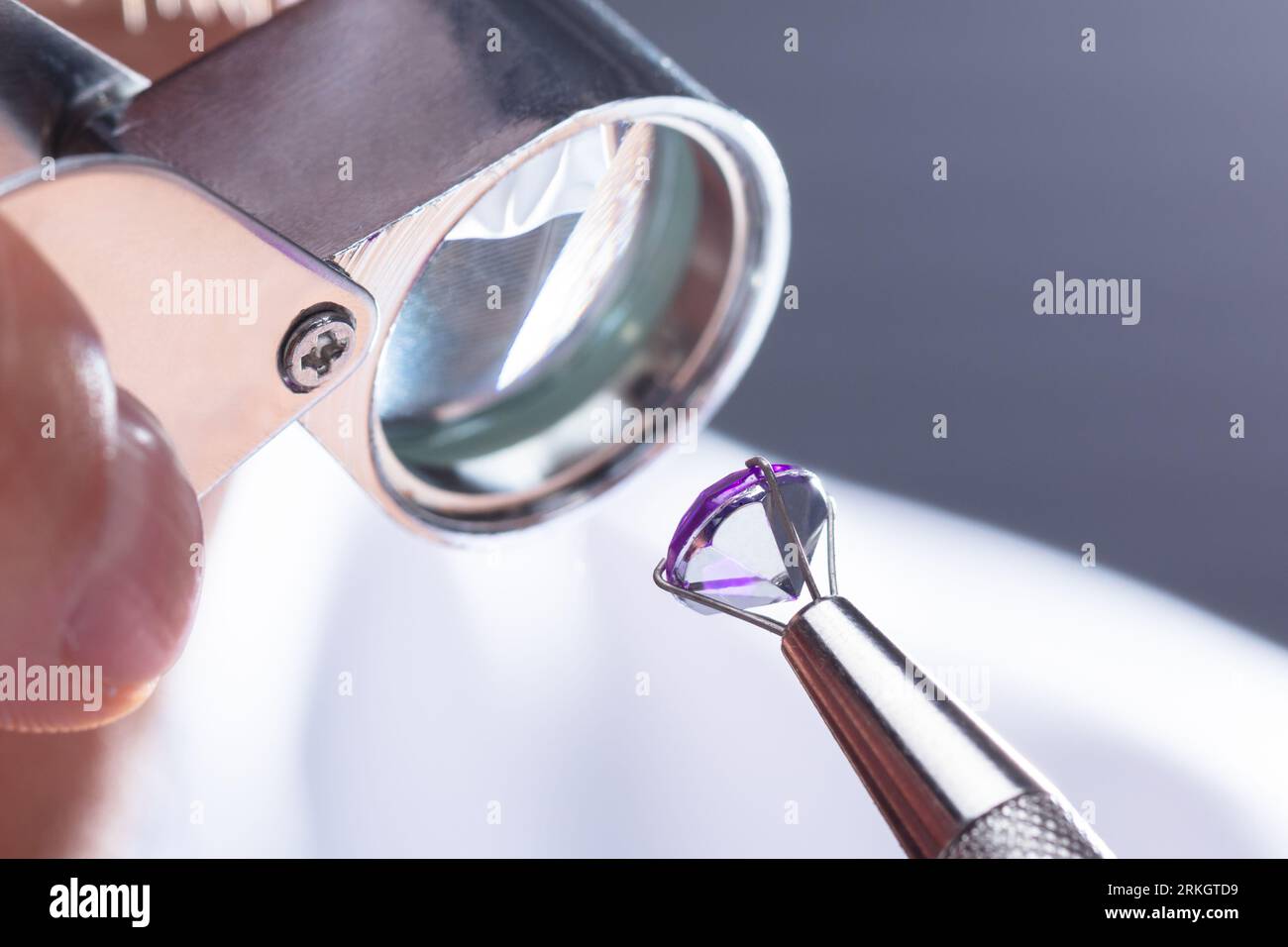 Closeup Of A Male Jeweler's Hand Looking At Diamond Through Magnifying