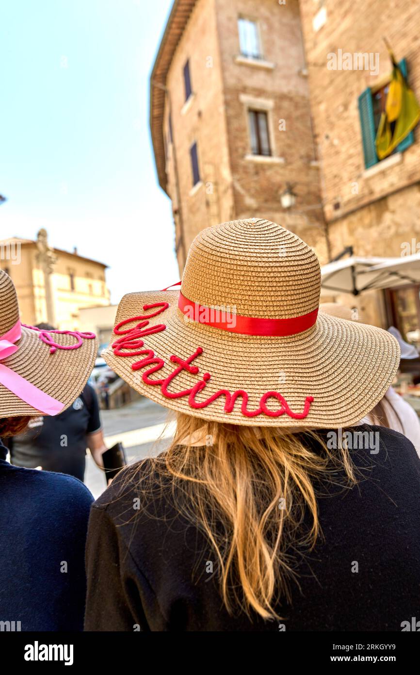 Two female friends wearing fashionable wide-brimmed hats walking down a cobblestoned street in a quaint old town Stock Photo
