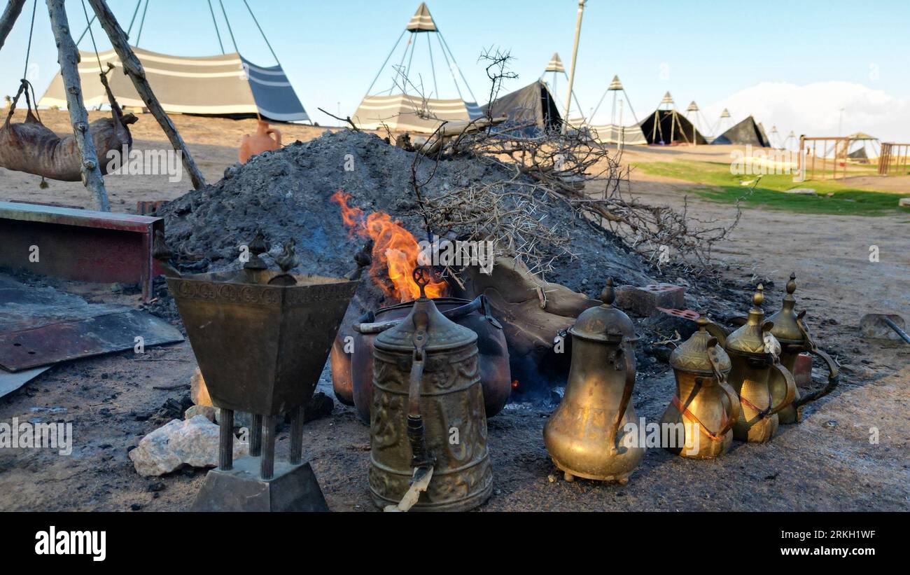 An outdoor charcoal grill with several cast iron pots filled with fire