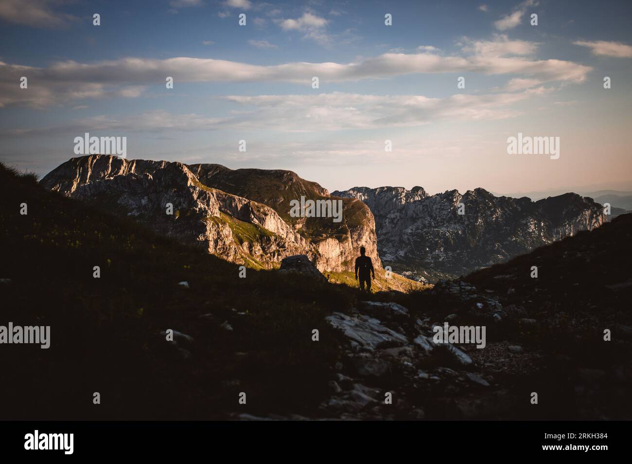 A young man striding through a mountainous landscape Stock Photo
