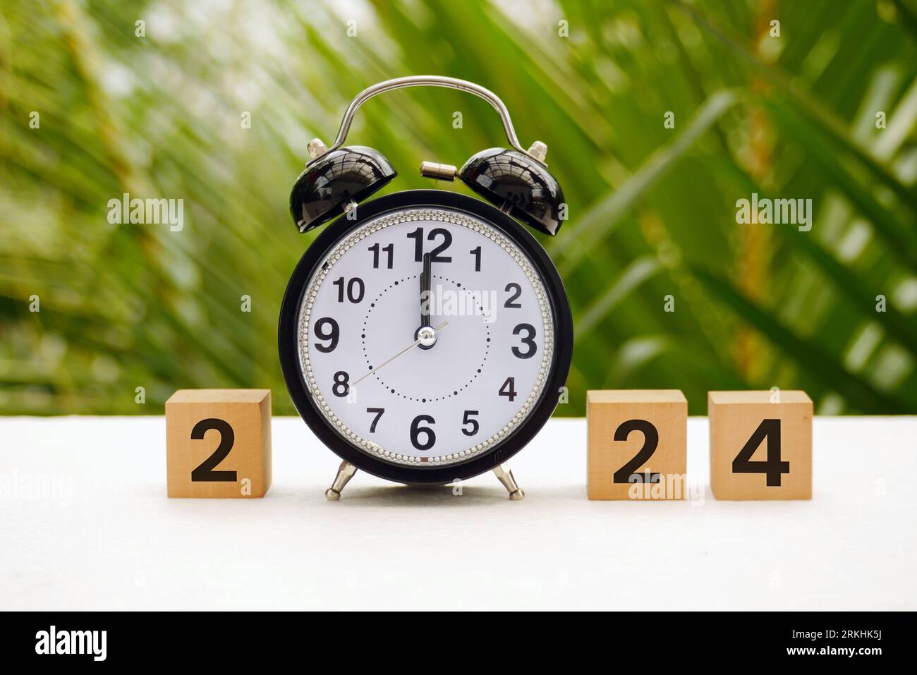 Happy New Year with a vintage alarm clock 2024 block with nature background. Resolution, time