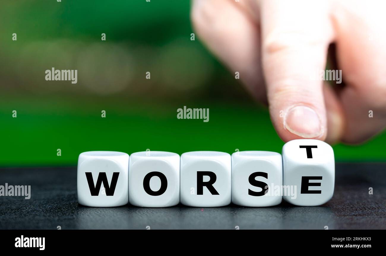 Hand turns dice and changes the word worse to worst. Stock Photo