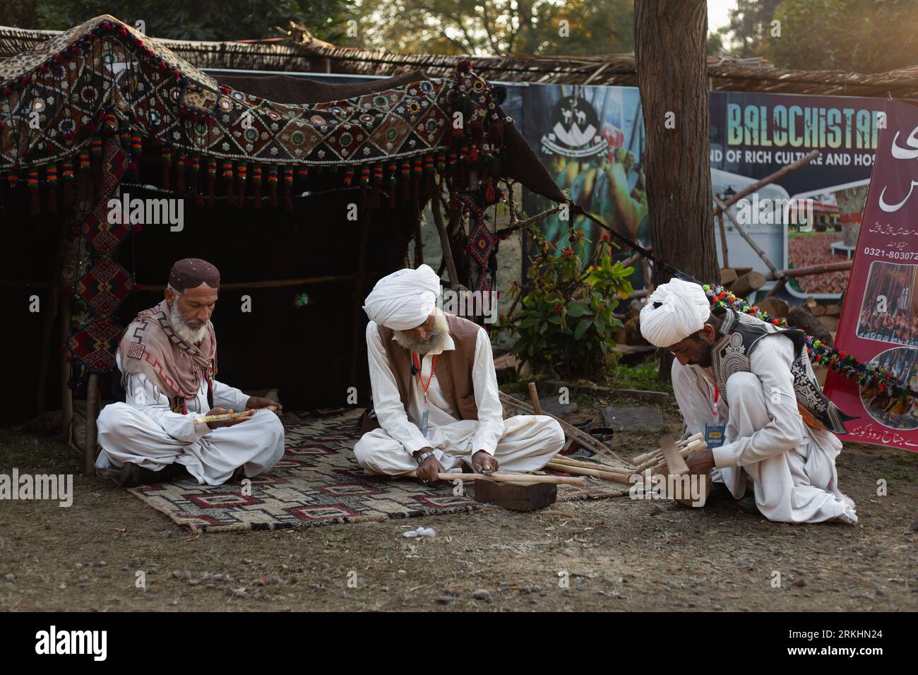 The people in turbans sitting on a rug outdoors at Lok mela in Islamabad, Pakistan Stock Photo