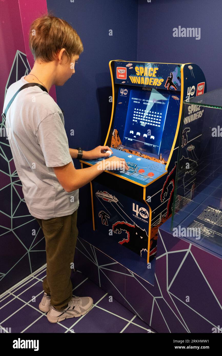 Space invaders Taito game machine. Simple Space Arcade in 8-bit retro video old game. Boy plays classic slot machine. Warsaw, Poland - July 28, 2023. Stock Photo