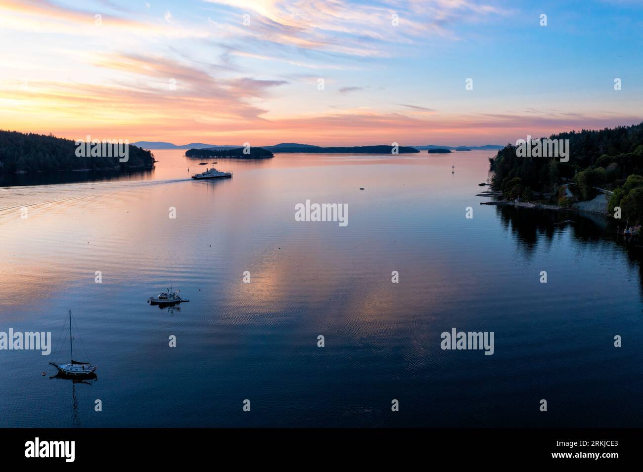 A beautiful sunset over a tranquil lake surrounded by a forest of trees ...