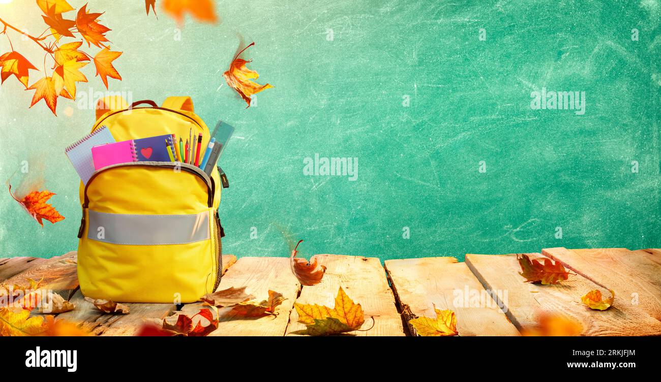 Schoolbag On Table With Stationary And Leaves - Backpack For Back To School Concept Stock Photo
