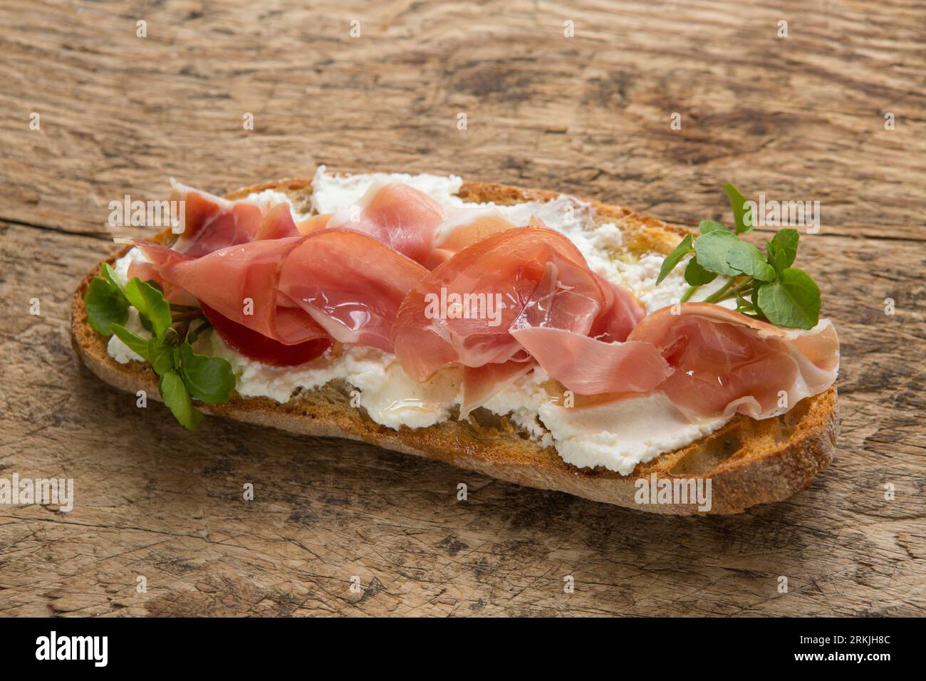An example of bruschetta made with toasted sourdough bread, ricotta cheese and Serrano ham. Drizzled with olive oil and garnished with watercress. Pre Stock Photo