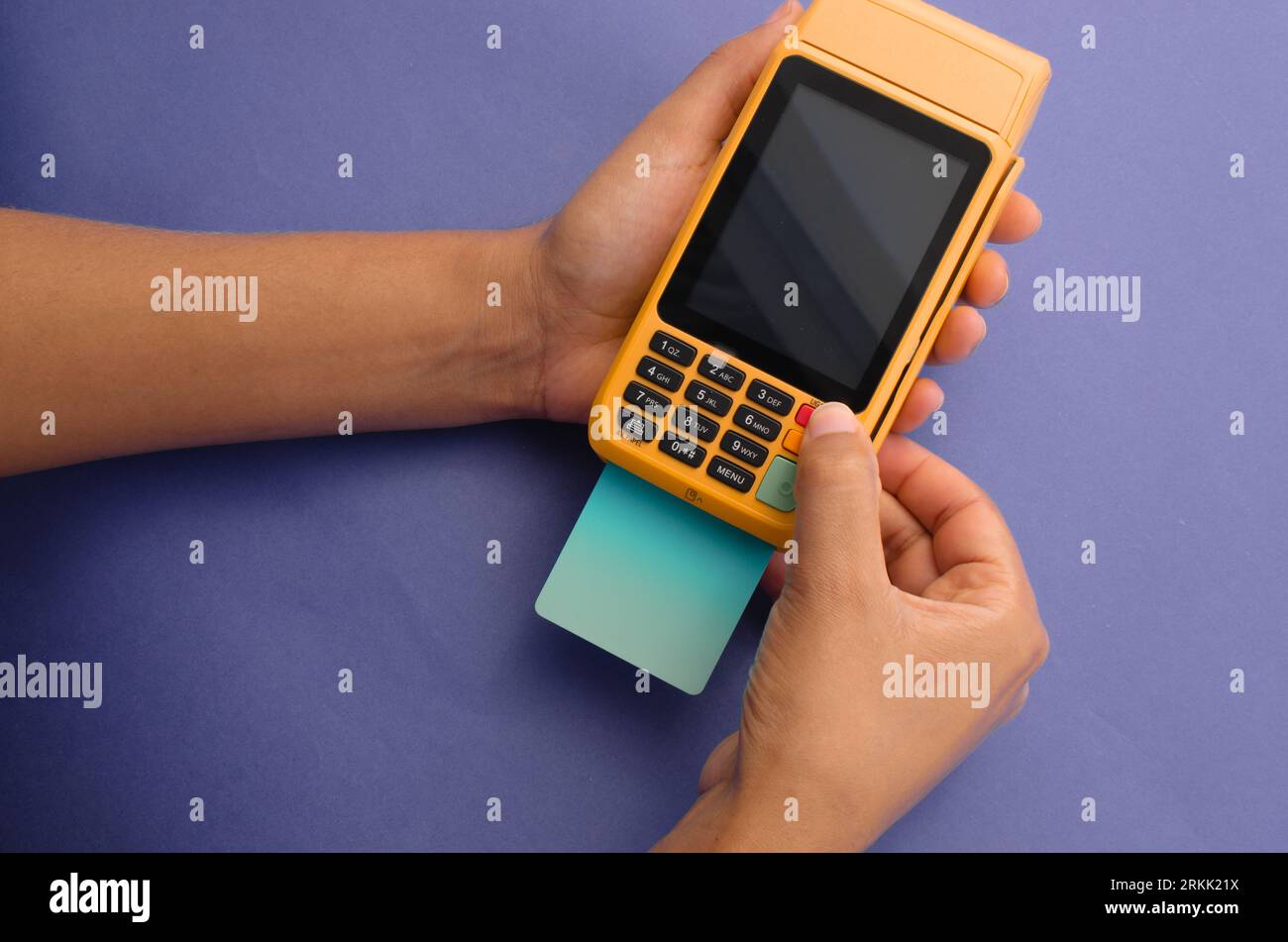 Hand holding yellow contactless payment device for credit cards