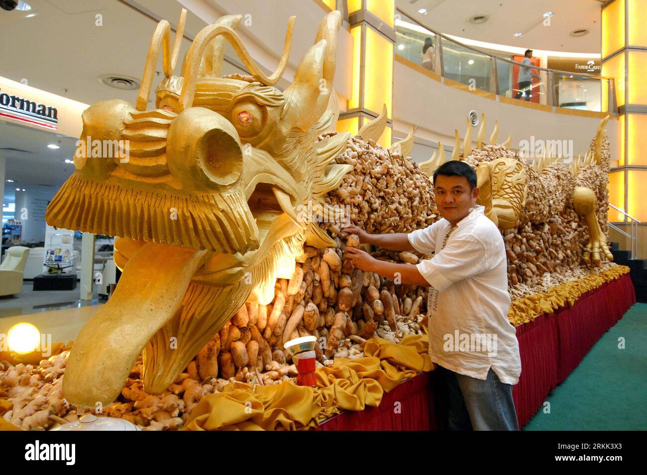 Bildnummer: 56195771  Datum: 19.10.2011  Copyright: imago/Xinhua (111019) -- KUALA LUMPUR, Oct. 19, 2011 (Xinhua) -- A staff member has a picture taken with a huge dragon sculpture which is made of ginger and lotus root in a shop in Kuala Lumpur, Malaysia, Oct. 19, 2011. The dragon sculpture measures 10.688 meters long and it took 20 workers in 2 months time in making. (Xinhua/Chong Voon Chung) MALAYSIA-KUALA LUMPUR-DRAGON MADE OF GINGER PUBLICATIONxNOTxINxCHN Gesellschaft Skulptur Figur Drachen Ingwer Lotoswurzel Kurios xbs x0x 2011 quer      56195771 Date 19 10 2011 Copyright Imago XINHUA  K Stock Photo