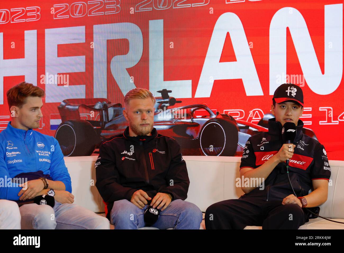 ZANDVOORT, NETHERLANDS - AUGUST 24: Zhou Guanyu of Alfa Romeo F1 Team Kick talking and Logan Sargeant of Williams Racing  and Kevin Magnussen of Money Stock Photo