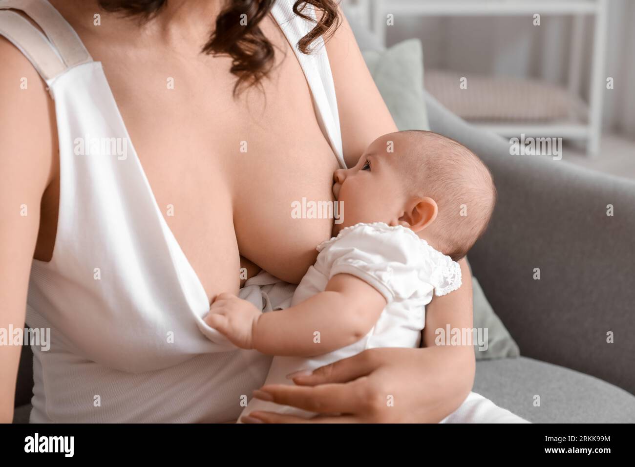 Young woman breastfeeding her baby at home, closeup Stock Photo
