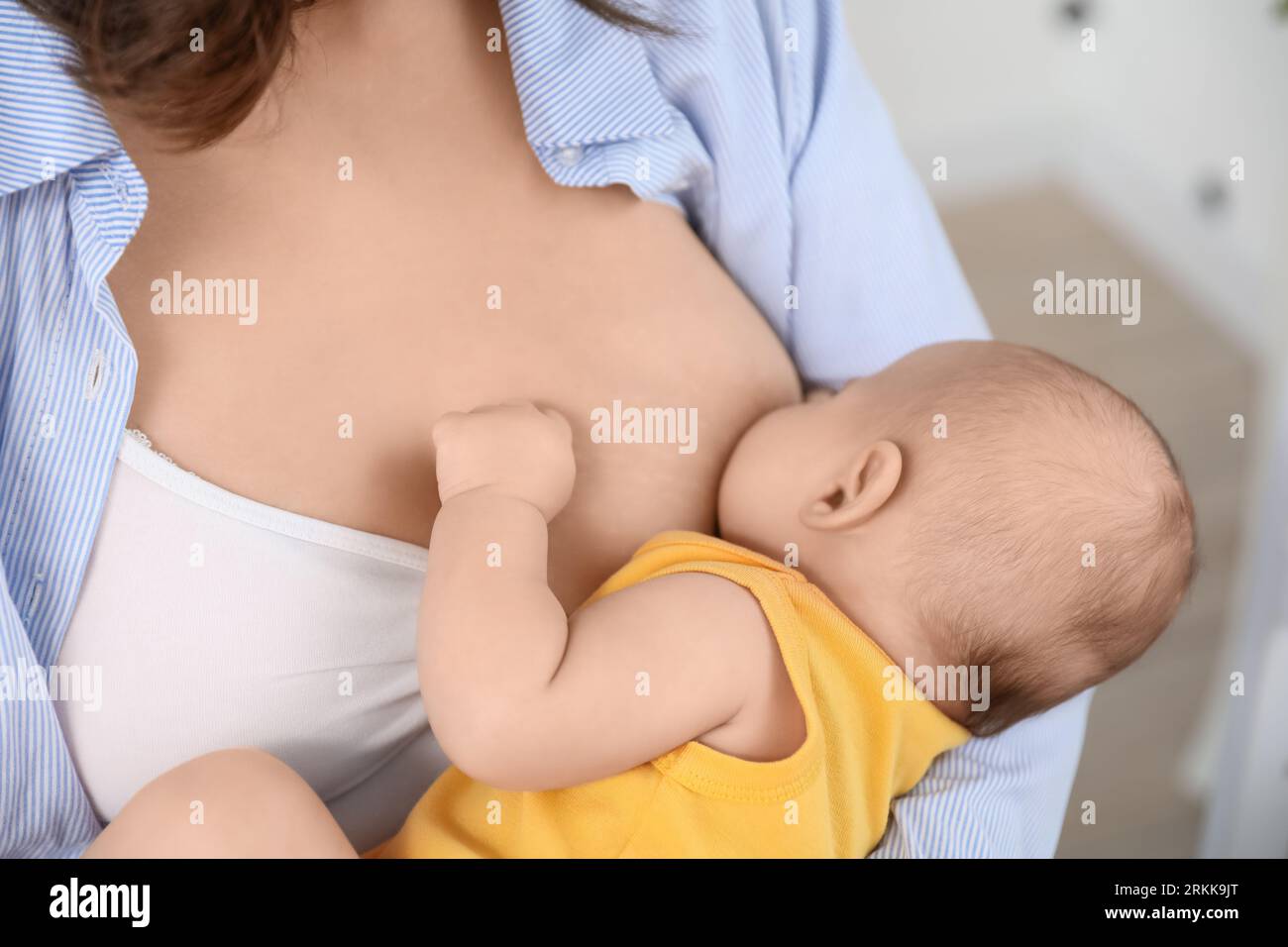 Young woman breastfeeding her baby in bedroom, closeup Stock Photo