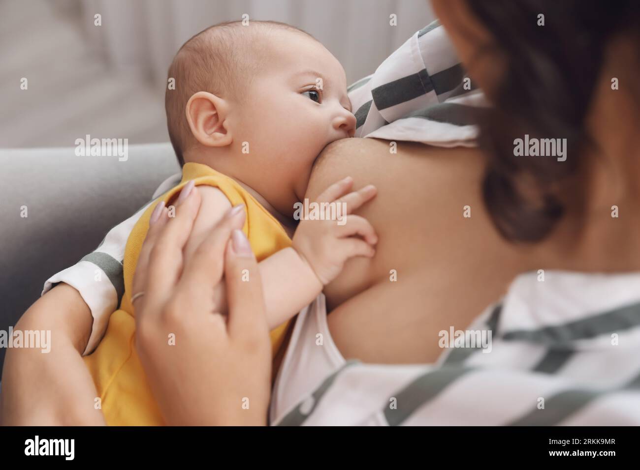 Young woman breastfeeding her baby at home, closeup Stock Photo