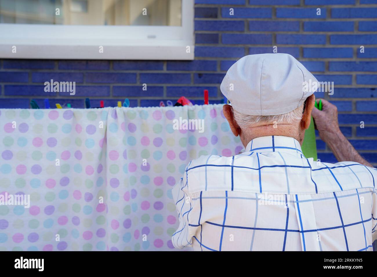 Active elderly doing household. Unrecognizable retired man hanging up the laundry. Cooperation, responsibility and equality in domestic life Stock Photo