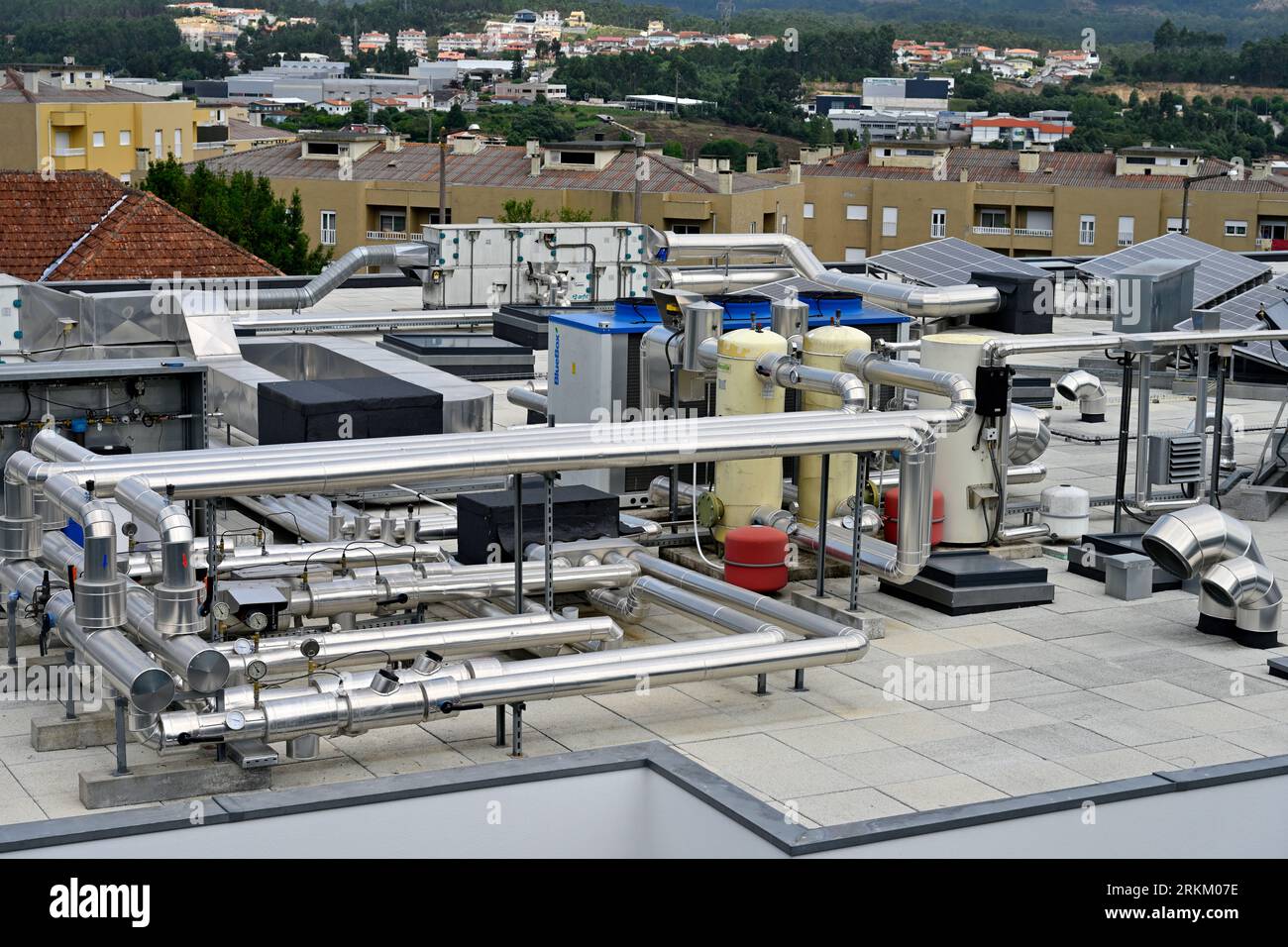 The complexity of pipes and cylinders atop a building with solar thermal panels and heat pumps Stock Photo