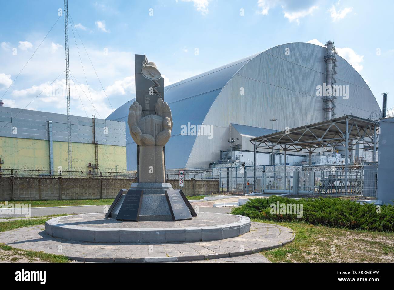 Monument to professionals who protected the world from nuclear disaster and Reactor 4 New Safe Confinement - Chernobyl Exclusion Zone, Ukraine Stock Photo