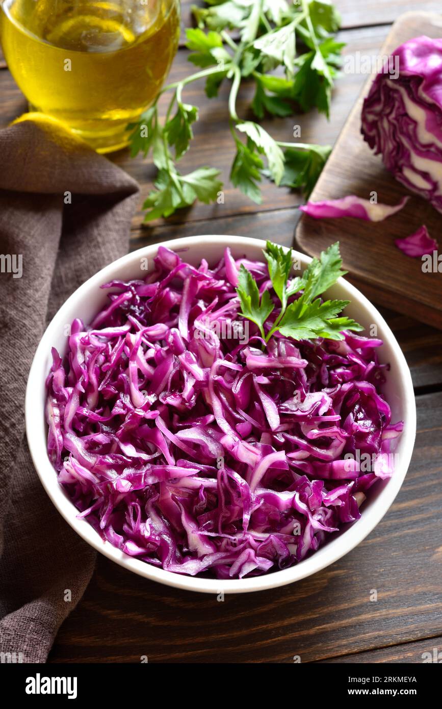 Raw red cabbage in bowl on wooden table. Close up view Stock Photo