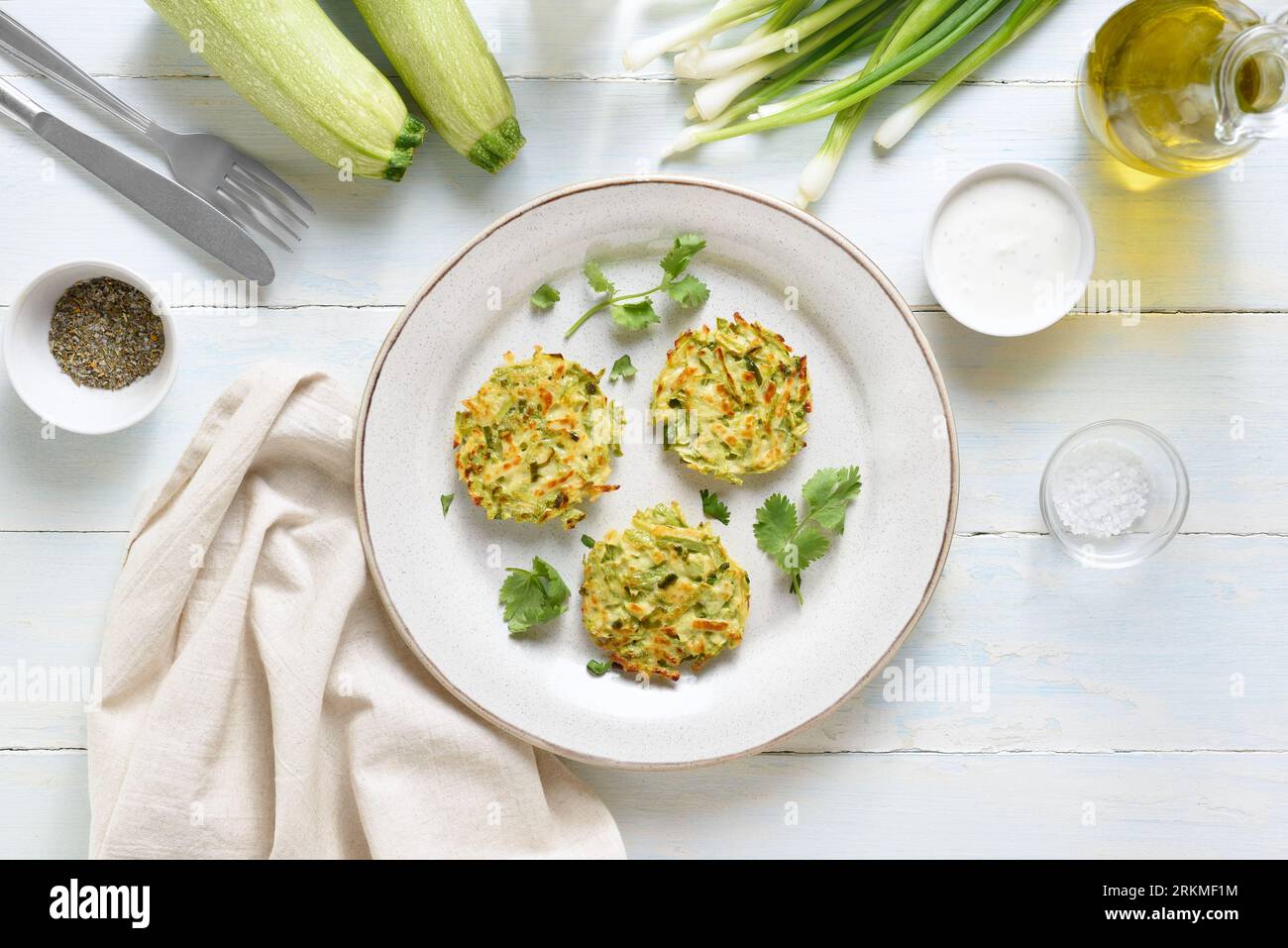 Vegetable vegetarian zucchini pancakes fritters on plate over light wooden background. Top view, flat lay Stock Photo