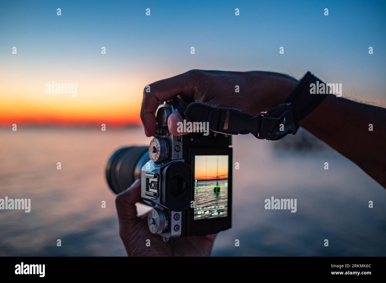 Take photos nature. Man hands holding digital camera makes photos of a sea and beautiful nature during sunset. Photographer is taking photo of summer Stock Photo
