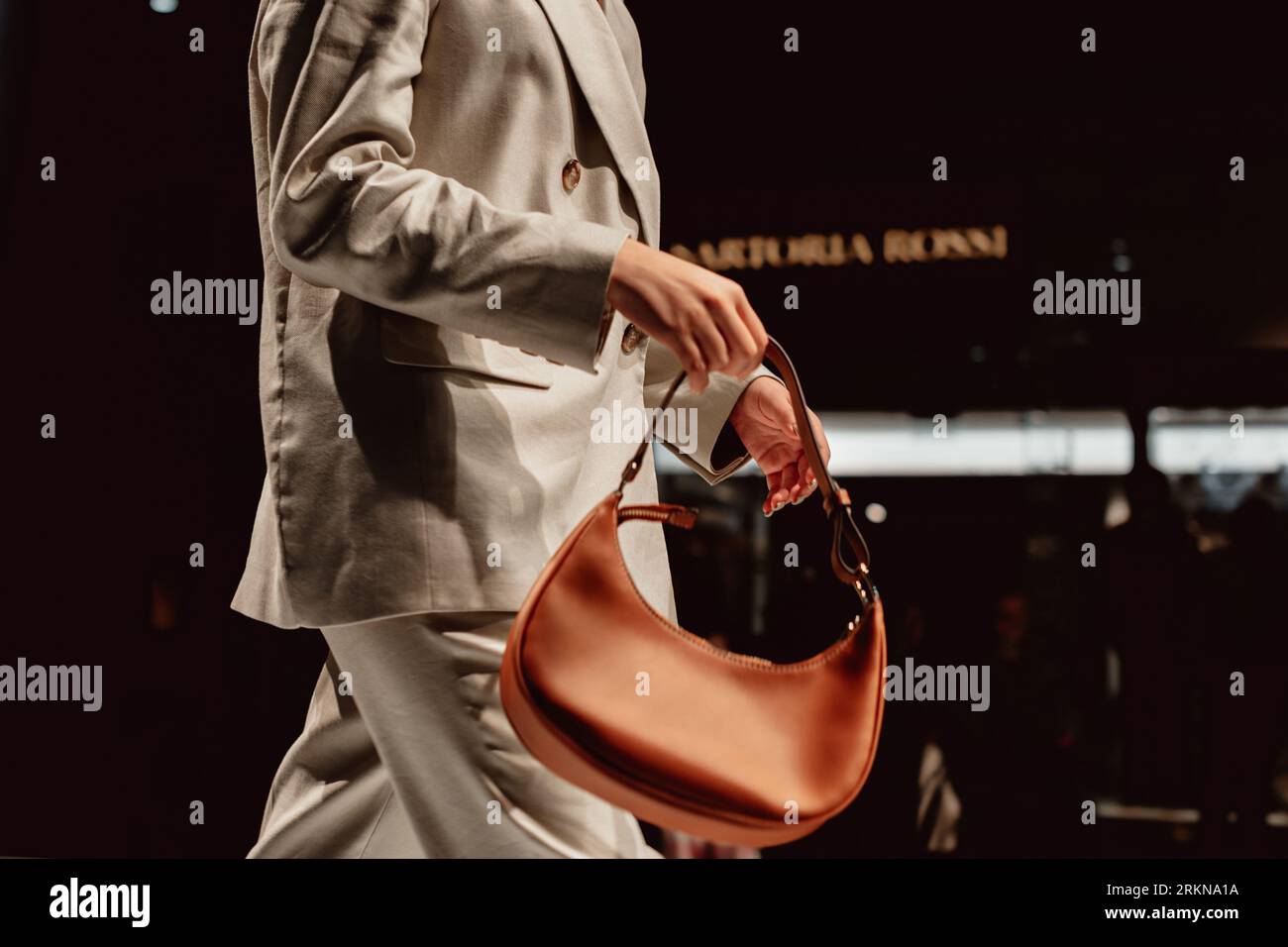 Fashion model walking in classy beige suite and holding brown leather handbag Stock Photo