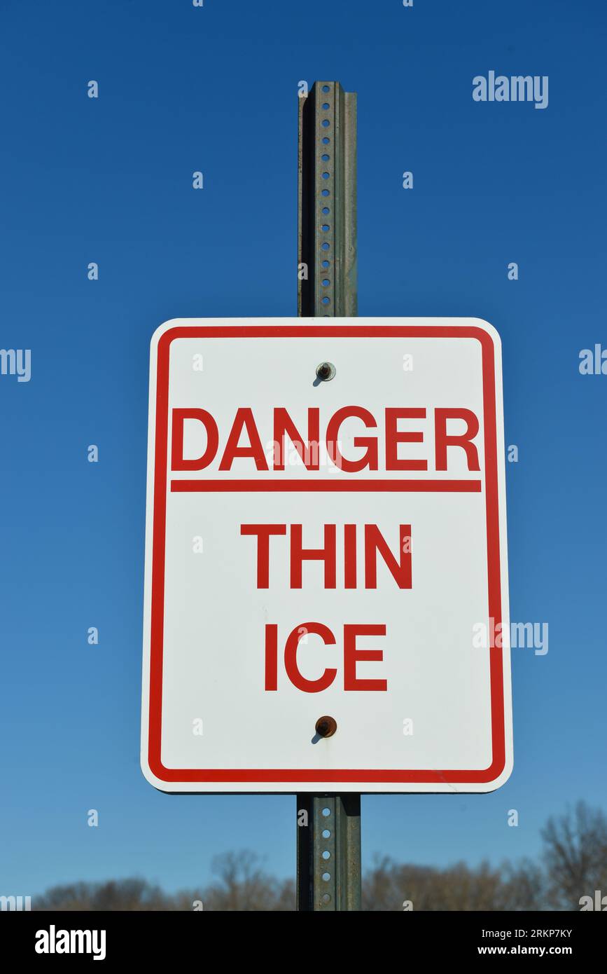Danger thin ice  warning sign by a lake near woods. Stock Photo
