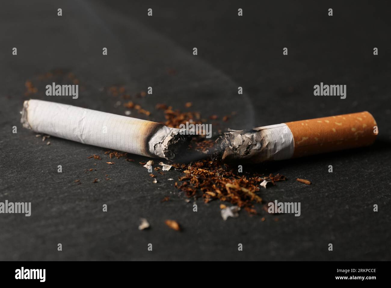 burnt tobacco Burnt cigarette, tobacco and smoke on black table, closeup. No smoking  concept Stock Photo