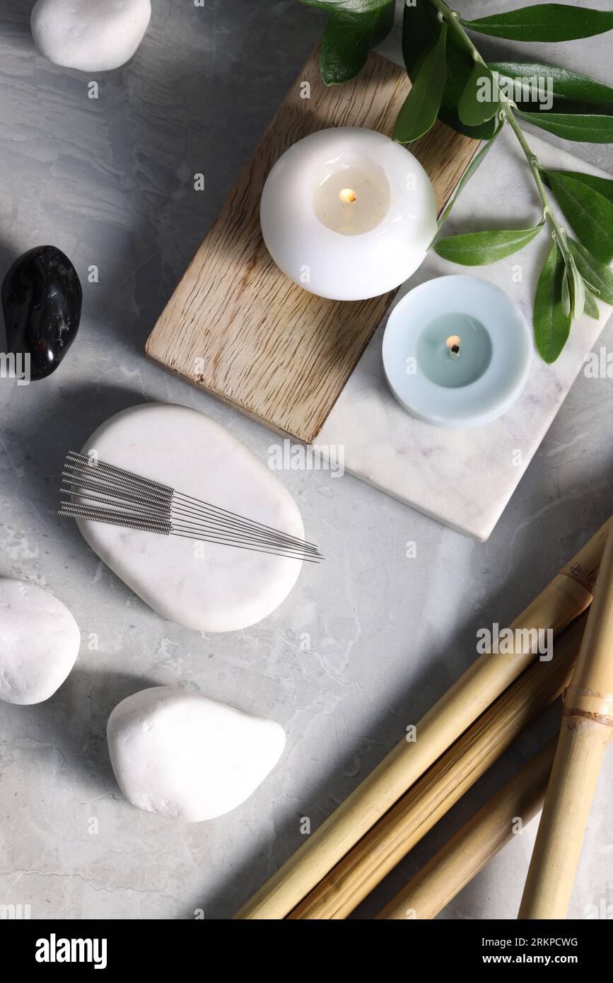 Flat lay composition with acupuncture needles on light grey marble ...