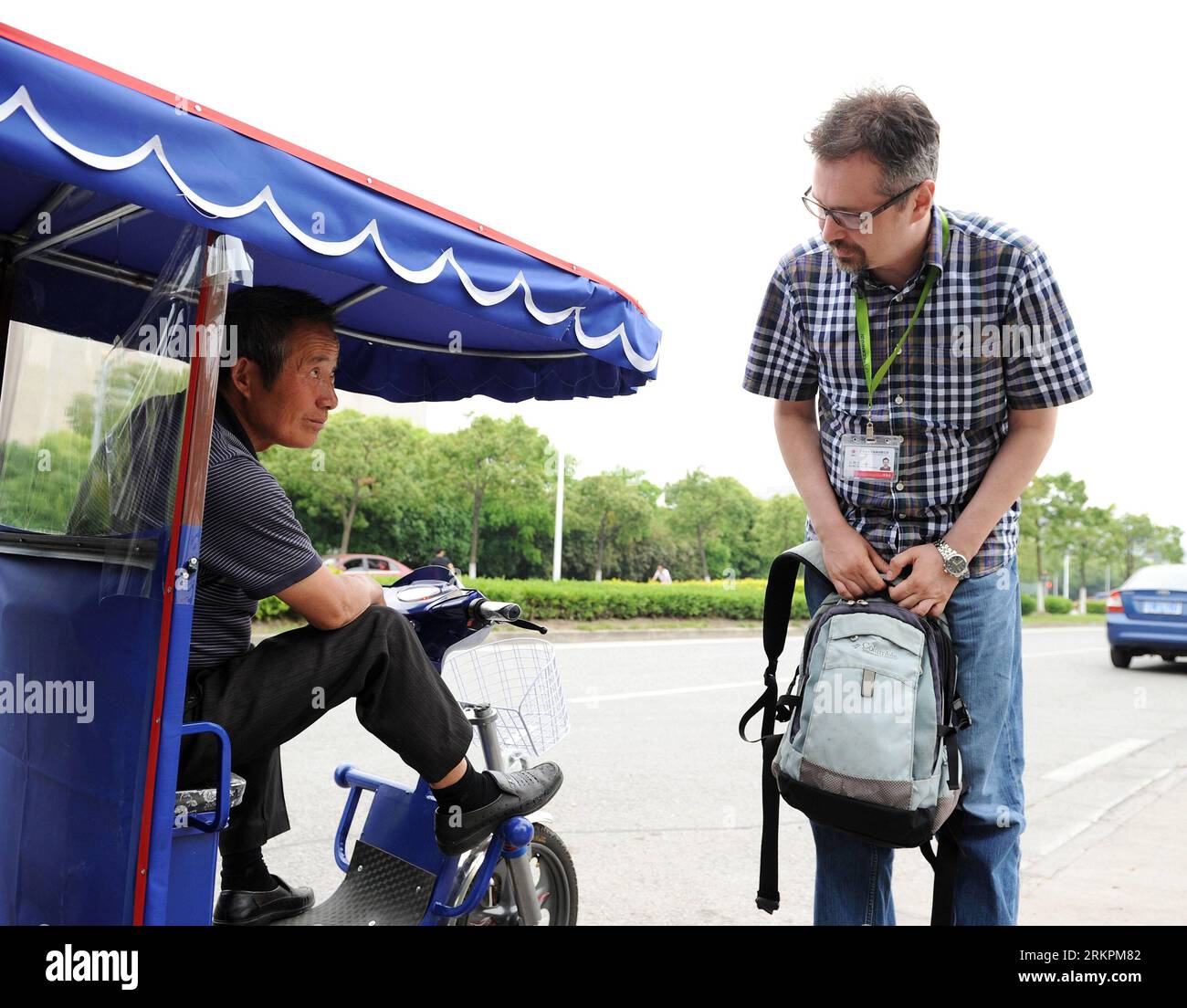 Bildnummer: 58021960  Datum: 07.05.2012  Copyright: imago/Xinhua (120522) -- SHANGHAI, May 22, 2012 (Xinhua) -- Anatoly Burov (R) makes inquires of a motorcycle driver about the price in Shanghai, east China, May 7, 2012. The 39-year-old Anatoly Burov comes from St.Petersburg of Russia. After graduation from the Rochester Institute of Technology in 2008, he founded an electronic technology company with his tutor in the United States. To negotiate business with the company s client, Anatoly came to Shanghai for the first time in the same year. This short-term experience made him love the port c Stock Photo