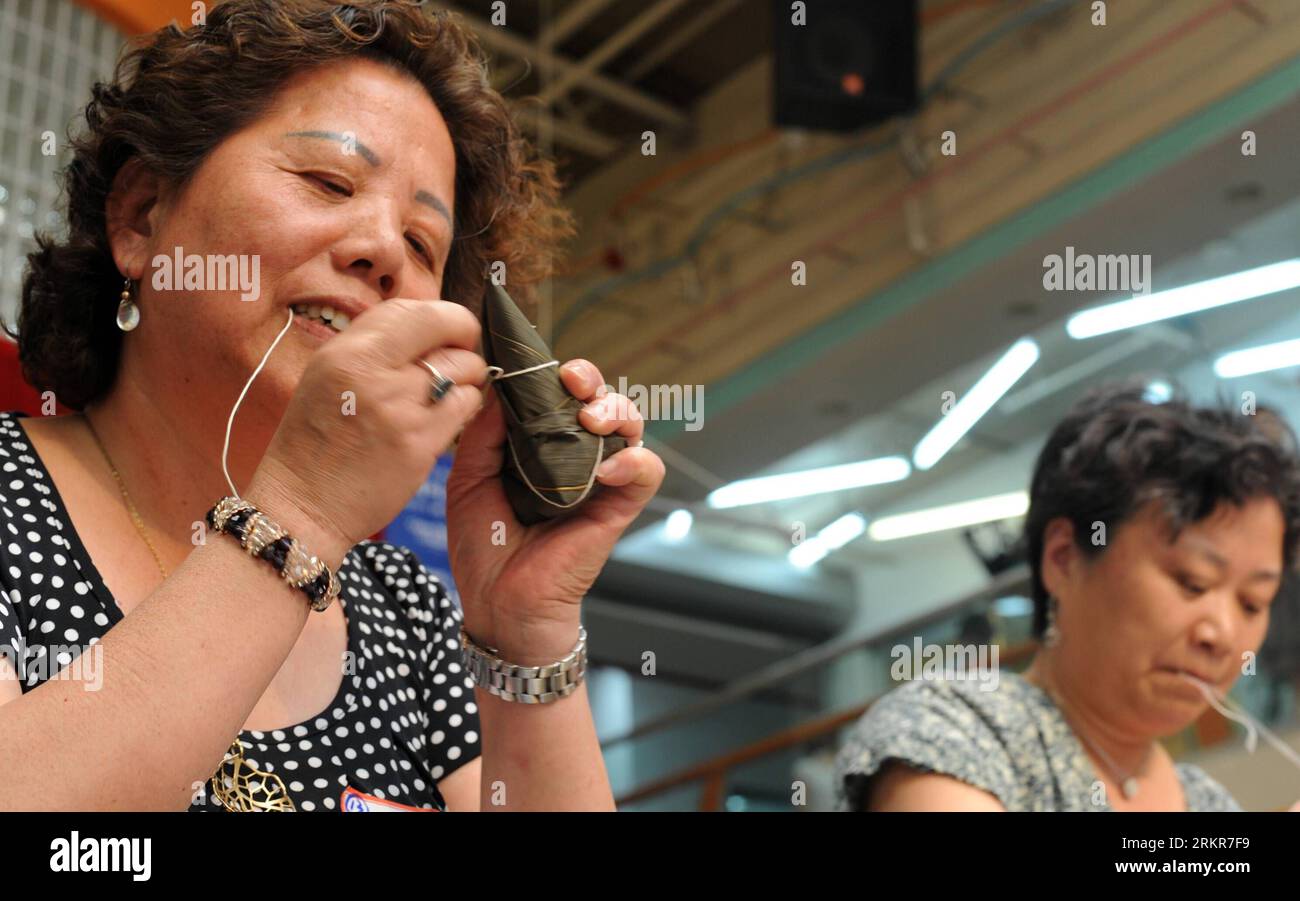 Bildnummer: 58142478  Datum: 23.06.2012  Copyright: imago/Xinhua (120623) -- NEW YORK, June 23, 2012 (Xinhua) -- Women make zongzi, a traditional Chinese rice-pudding during a game in celebration of the Dragon Boat Festival in Flushing, New York, the United States, June 23, 2012. (Xinhua/Wang Fang) U.S.-NEW YORK-CHINESE-DRAGON BOAT FESTIVAL PUBLICATIONxNOTxINxCHN Gesellschaft Tradition Drachenbootfest Food Klebreis Bananenblätter Zubereitung xda x0x 2012 quer      58142478 Date 23 06 2012 Copyright Imago XINHUA  New York June 23 2012 XINHUA Women Make Zongzi a Traditional Chinese Rice Pudding Stock Photo